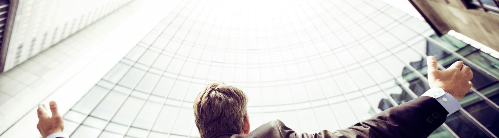 White male with blond hair raising his hands up to skyscrapers.