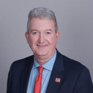 Man with gray hair blue suit and red tie.